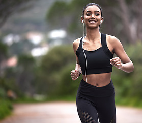 Image showing Running in nature, woman with earphones and fitness, mockup space and smile on healthy workout on path. Exercise, health and wellness, happy girl runner on forest path with music and training mindset