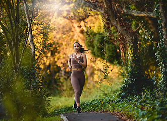 Image showing Woman, fitness and running in forest for cardio exercise, workout or training in the nature outdoors. Female person, athlete or runner exercising for healthy wellness, marathon or run in the woods