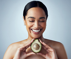 Image showing Smile, hands and woman with avocado in studio for skincare, organic or facial on grey background. Face, avo and girl model with fruit for eco, vegan or detox with omega 3, collagen and vitamin c