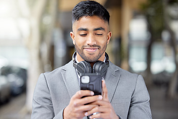 Image showing Business man, phone and city of a professional with headphones watching a video. Urban, smile and Indian male person with work travel, mobile streaming and happiness with cellphone app and web