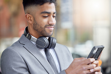 Image showing Business man, phone typing and city of a professional with headphones watching a video. Urban, smile and Indian male person with work travel, mobile and happiness with cellphone web and mockup