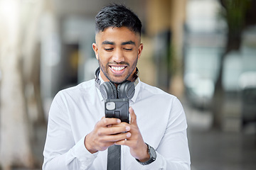 Image showing Business man, phone text and city of a professional with headphones watching a video. Urban, smile and Indian male person with work travel, mobile streaming and happiness with cellphone app and web