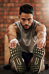 Image showing Gym, feet and portrait of man stretching, workout warm up and motivation for fitness mindset. Focus, commitment and face of athlete on floor, stretch and training legs at sports club for health goals