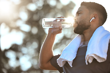 Image showing Man, fitness and drinking water in nature for sustainability, hydration or break after running workout or exercise. Male person or runner with natural drink for healthy wellness or rest from run