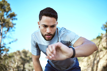 Image showing Fitness watch, man and outdoor for a run or workout with earphones and app for progress. Tired male athlete person check time in nature forest for cardio training, running or health and wellness goal