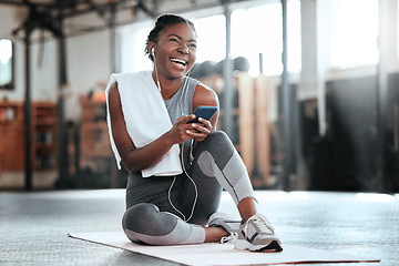 Image showing Phone, earphones and funny black woman in gym for fitness, sports or exercise. Smartphone, music and African female athlete laughing at web meme or comedy on break after workout, training or pilates.