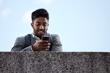 Image showing Phone, networking and businessman by a wall in the city browsing on social media or mobile app. Happy, smile and professional male employee scrolling on the internet while waiting for a cab in town.