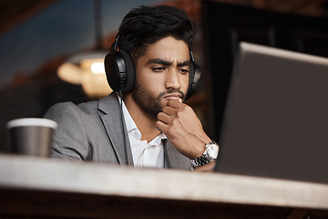 Image showing Young business man, thinking and coffee shop with headphones, laptop or plan for schedule, report or analysis. Indian businessman, solution and ideas with brainstorming, web design and music in cafe