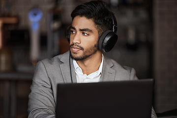 Image showing Business man, thinking and cafe for remote work with headphones on laptop, planning and report. Young indian businessman, solution and brainstorming for ideas, web design and music in coffee shop