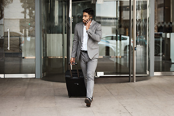 Image showing Phone call, travel and luggage with a business man walking in the city for an international trip. Mobile, communication and suitcase with a young male employee talking while on a global commute