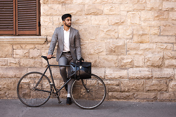 Image showing Bicycle, suit and businessman in the city for travel standing by a brick wall building. Briefcase, professional and young male employee riding a bike or commuting to his work office in an urban town.