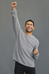 Image showing Celebrate, winner and man in a studio cheering for success, winning or champion achievement. Happiness, excited and male model with fist pump in celebration of a victory isolated by a gray background