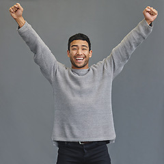 Image showing Celebration, happy and portrait of a man in a studio cheering for success, winning or achievement. Happiness, excited and male model winner with fist pump to celebrate a victory by a gray background.