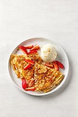 Image showing crepes decorated with honey, strawberries and ice cream