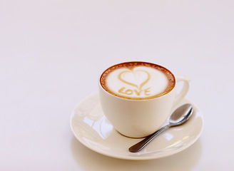 Image showing Coffee cup, cappuccino and heart in foam in studio isolated with white background. Cafe drink, love writing and foamy beverage art with milk and mockup with a closeup of mug, message and spoon