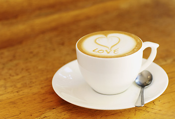 Image showing Coffee, latte and wooden table at vintage cafe with a cup at a restaurant with a plain background. Expresso, kitchen and drink with milk and foam at retro diner for breakfast in the morning with love