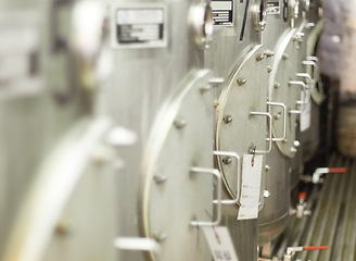 Image showing Closeup, stainless steel and fermentation tanks for brewing beer at a breweries, factory or warehouse. Alcohol, machine and barrel at a manufacturing plant for process, fermentation and procedure