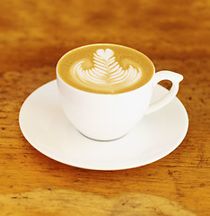 Image showing Coffee, cafe and latte art in a cup on wooden table background in restaurant to drink espresso with foam. Retro, diner and mug with saucer in kitchen with vintage design during morning breakfast.