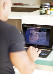 Image showing Man, laptop screen and research on website product or supplements on kitchen table at home. Rear view of male person searching on computer for online information, browsing or pharmaceutical knowledge