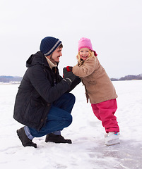 Image showing Father with daughter outdoor, learn to ice skate and fun in nature with snow, winter and people skating on frozen lake. Man have fun with girl child, teaching and learning with sports and recreation