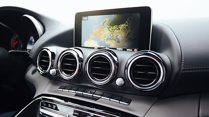 Image showing View from inside a car on a part of dashboard with a navigation unit and blurred street in front of a car