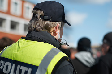 Image showing Law enforcement, protection or crowd control with police officer in city for peace, safety and authority. Emergency services, justice and guard with back of person in street at rally, order or arrest