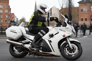 Image showing Police, motorcycle and safety officer working for protection and peace in an urban neighborhood in the UK. Security, law and legal professional or policeman on a motorbike ready for service