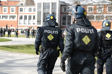 Image showing Law enforcement, riot and protest with police officer in city for safety, protection or security. Brave, uniform and government with group of policeman in street for rally, human rights or activist