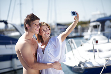 Image showing Camera, selfie and couple hug, smile and pose at harbor for travel, honeymoon or trip together. Love, picture and traveling influencer people embrace for photo before cruise ship, vacation or holiday