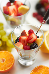 Image showing Fruit salad, breakfast and healthy food or diet in studio with color, art and creativity. Nutritionist, wellness and fruits for vegan snack with berry, apple and orange ingredient on a white table