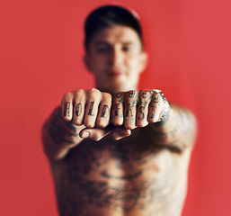 Image showing Fist, tattoo or blurred man in studio isolated on red background with unique, cool or artistic creativity. Zoom, rebel or portrait of trendy macho person showing hands or knuckles with ink or tattoos