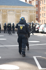 Image showing Security, authority and back of police officer in the city working to patrol a protest or march. Law enforcement, public service and safety guard in uniform for protection in an urban town street.