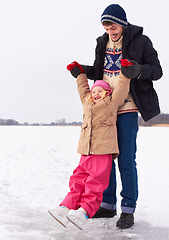 Image showing Man with girl outdoor, learn to ice skate and fun in nature with snow, sports and recreation. Father spending quality time with daughter, teaching and learning skating on frozen lake during winter