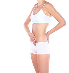 Image showing Woman, flat stomach and hands in studio with waist, measuring or fitness for wellness by white background. Isolated model, girl and underwear with touching, body or abdomen for healthy lifestyle