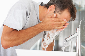 Image showing Hygiene, hydration and a man washing his face in the bathroom of his home in the morning to wake up. Fresh, water and cleaning with a male person in his house to start a skincare or moisture routine