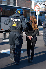 Image showing Police man arrest woman at protest in city, crime and law enforcement, security at demonstration in the street. Public servant, service and patrol for safety at event, activist and officer back view