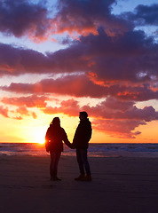 Image showing Couple, silhouette and sunset sky at the beach on a romantic date, vacation or holiday in nature. Man and woman holding hands with love and care on travel, adventure or trip with clouds and ocean