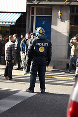 Image showing Safety, crowd control and protest with police officer in city for law enforcement, protection or security. Brave, uniform and riot with person in Denmark street for rally, human rights or activist