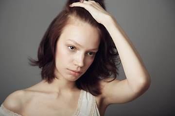 Image showing Sad woman, stress and anxiety with hand on hair in mental health problem isolated on a grey studio background. Anxious, stressed or depressed young female model holding head in thought on backdrop