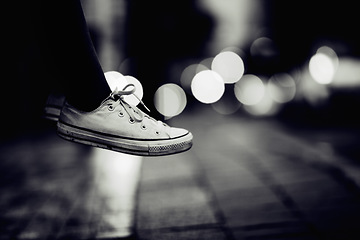 Image showing Closeup, monochrome and sneakers outdoor, city and lights with creativity, road and artistic. Zoom, person or model with shoes, street and grey with footwear, night or creative with fashion or travel