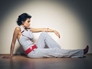 Image showing Spotlight, fashion and gen z girl on a studio floor with attitude, style and cool against a wall background. Edgy, cool and fashionable female model relax in designer outfit, beautiful and unique