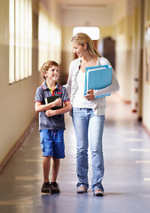 Image showing Teacher, child and walking in corridor at school, talking and bonding together. Education, smile and woman walk with kid, boy or student in hallway while going to class, speaking and discussion.