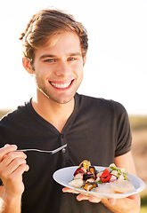 Image showing Portrait, smile and a man eating food outdoor on a summer day for health, diet or nutrition. Happy, morning and lifestyle with a handsome young person enjoying a fresh meal alone outside in nature