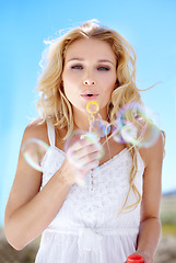 Image showing Summer, portrait and a woman blowing bubbles for happiness, fun and playful in nature. Beautiful, spring and a young lady with bubbles, playing and enjoying childlike energy in a garden or park