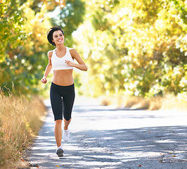 Image showing Woman, running and road with trees, space and speed for outdoor workout, health and smile in mockup. Girl runner, countryside street and happiness in summer sunshine for exercise, training or fitness