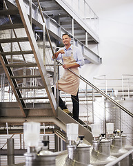 Image showing Portrait, wine and manufacturing with a man in a factory, plant or warehouse for production or fermentation. Industry, steel and equipment with a male manager standing on stairs for making alcohol