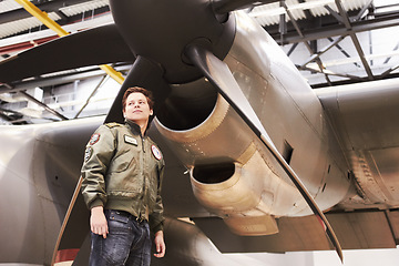 Image showing Army, jet and man pilot or combat plane or low angle in front of propeller and in navy uniform on tarmac. Military, jet fighter and in hangar or soldier in training gear and aircraft for mission