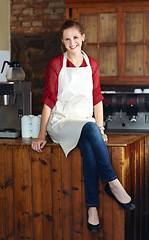 Image showing Woman in portrait, barista at coffee shop and sit on countertop, happy employee in hospitality industry. Female professional in cafe, small business owner and entrepreneur smile with positive mindset