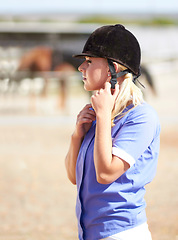 Image showing Woman prepare, horse jockey and helmet of young athlete on equestrian training ground for show and race. Outdoor, female person and equipment fixing on animal farm for dressage with rider and horses