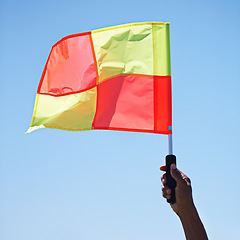 Image showing Flag, stop and soccer referee in football match or game wave a foul sign during sport training or workout. Hand, sports and person or assistant official raise or signal mistake in sky background